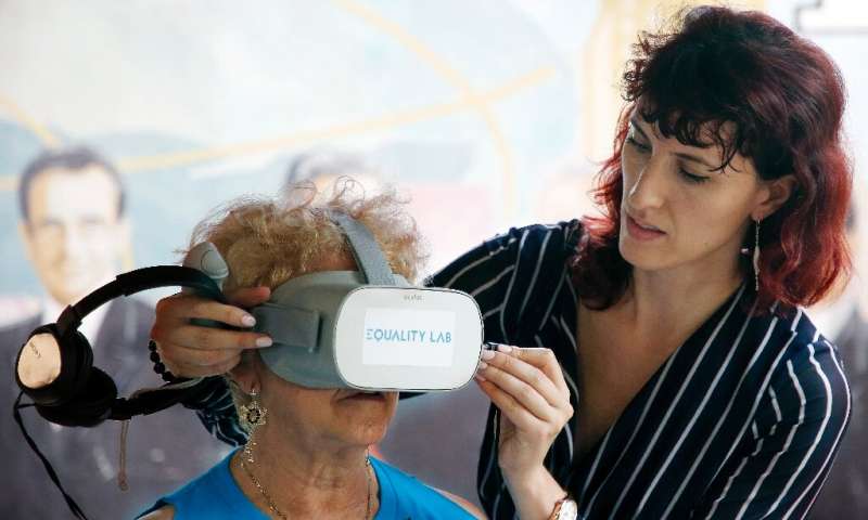 Alexandra Ivanovitch (D) assiste Nidia Silva (L) avec le casque de réalité virtuelle dans le quartier de Little Havana à Miami, Floride