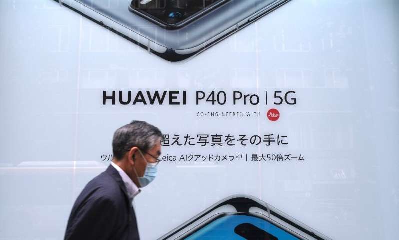 Cette photo prise le 27 juin 2020 montre un homme à Tokyo passant une publicité pour le smartphone compatible 5G de Huawei;  Apple est e
