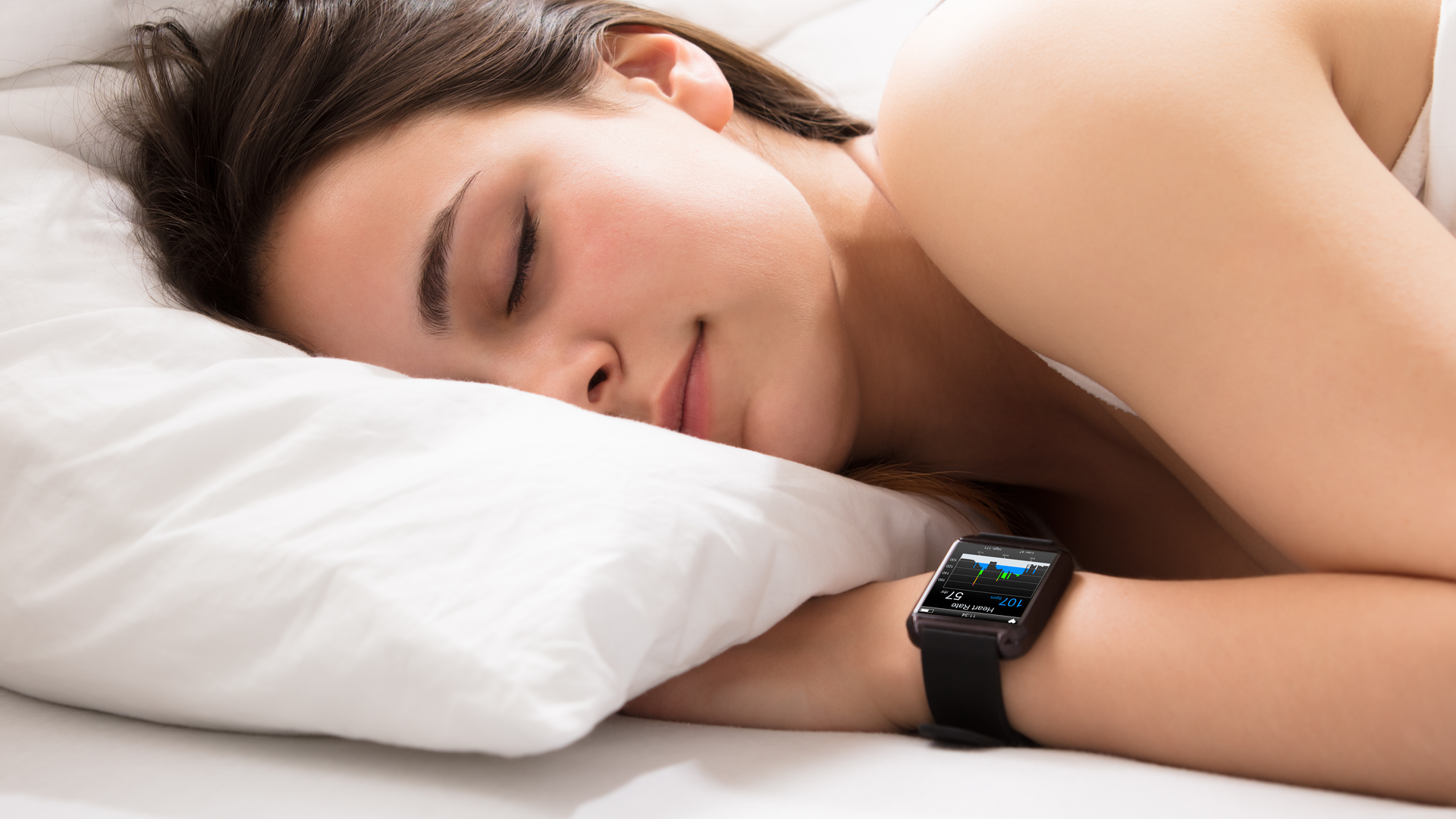 Personne endormie sur un lit avec une montre intelligente qui surveille son rythme cardiaque