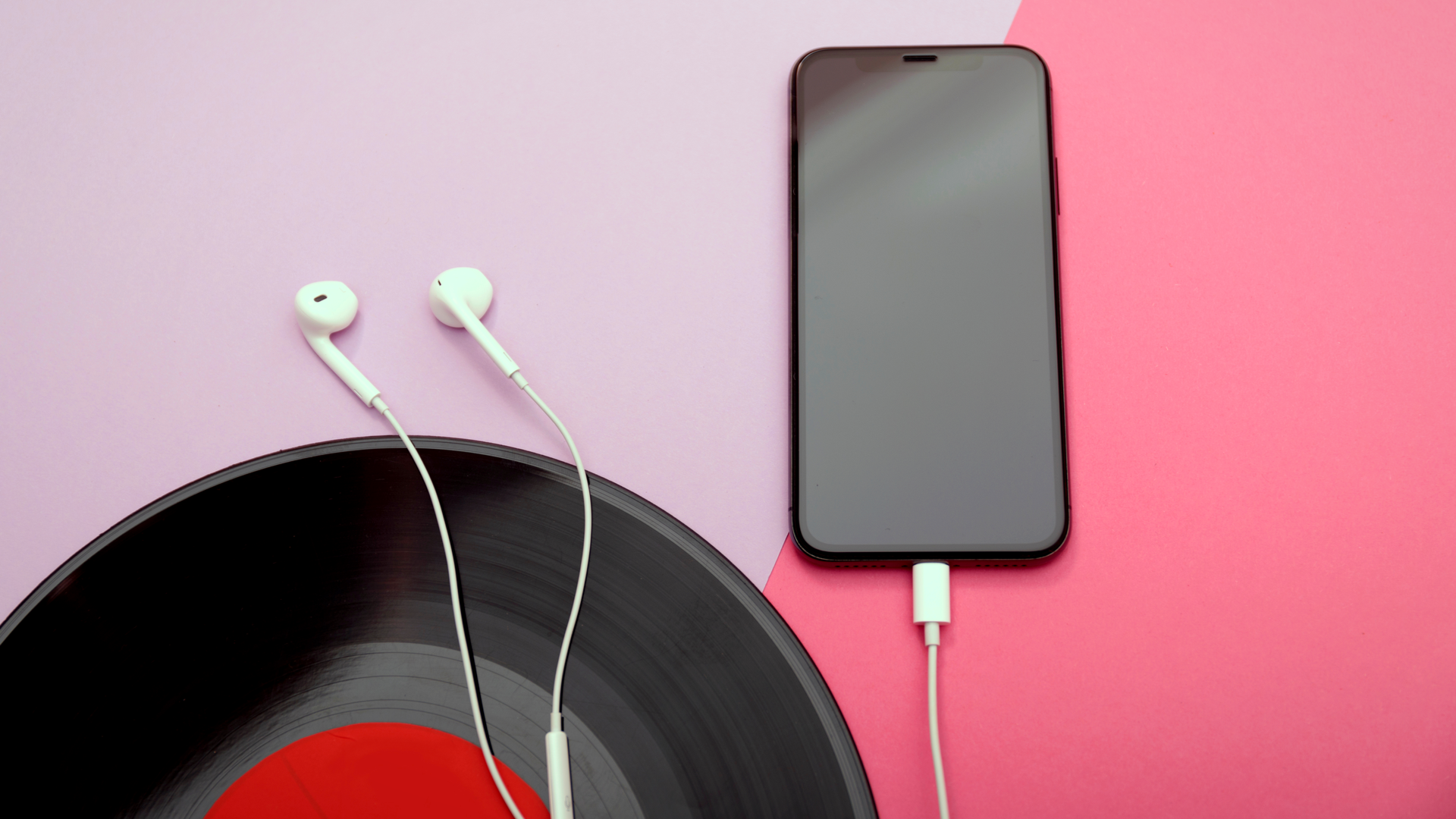 Smartphone, écouteurs et vinyle sur un fond coloré avec un espace de copie. Style rétro moderne et minimal dans des couleurs pastel. Concept de musique.
