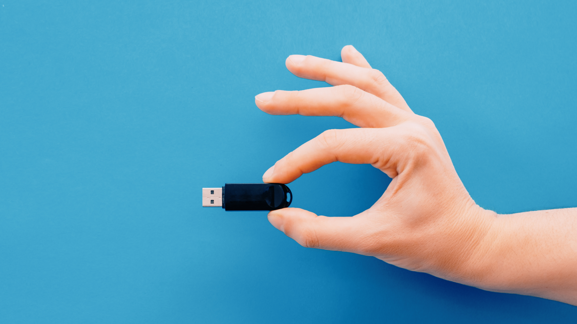 Concept de mémoire de données numériques. Main tenant une clé USB sur fond bleu.